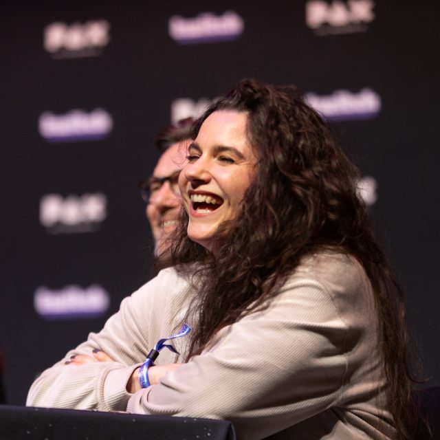 Voiceover artist laughing joyfully at a PAX Australia Panel about voice acting.